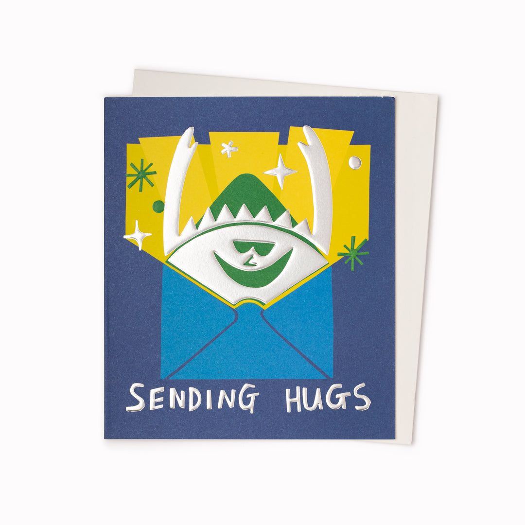 Sending Hugs Greeting Card is a silver foil hug appearing from an envelope featuring artwork by artist and screen printer, David Newton.